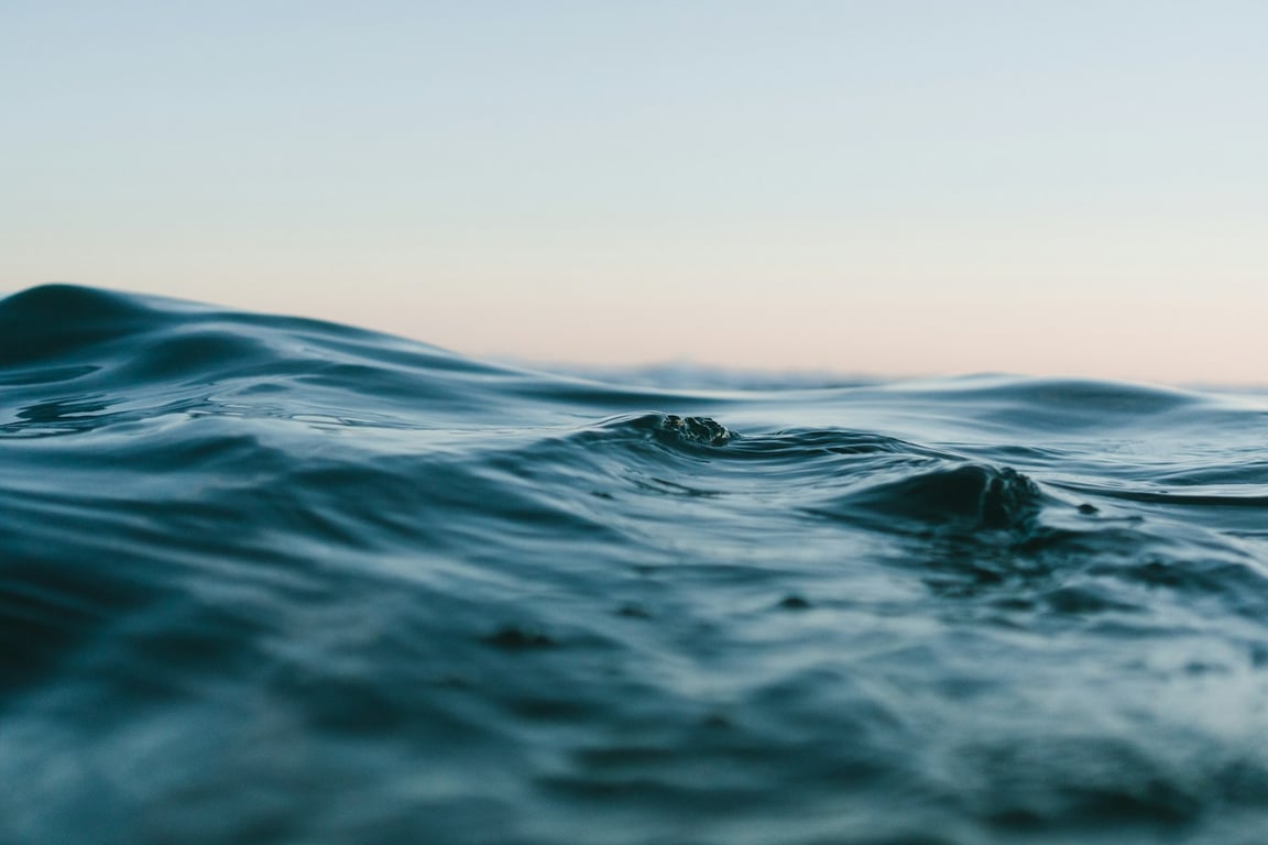 Soft blue ocean waves meeting a pale evening sky